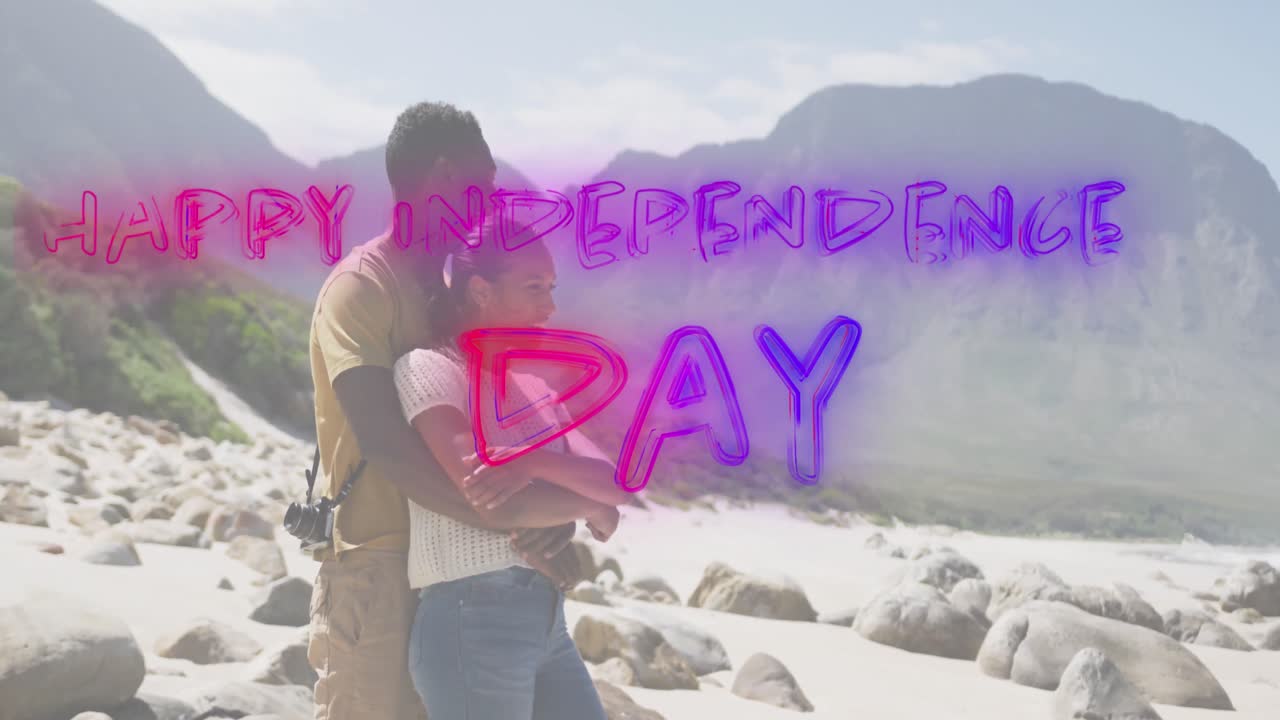 Animation of text independence day over african american couple embracing at beach