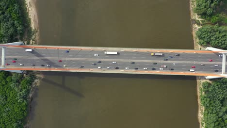 Coche-De-La-Ciudad-Moviéndose-En-El-Puente-De-La-Autopista-En-La-Superficie-Del-Río-Suave-De-Fondo-Vista-De-Drones