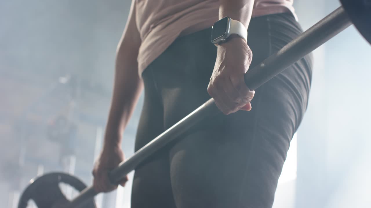 Gripping barbell at gym, athlete is lifting weight straightening legs and engaging glutes for power