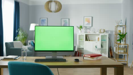 modern personal computer with mock-up green screen display standing on the desk of the cozy home office. living room of stylish interior designer.