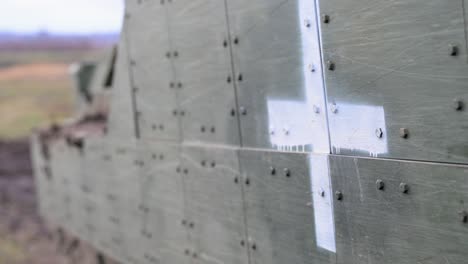 a close-up of a white cross stenciled on the side of an m2 bradley ifv in ukraine. this marking designates the fighting vehicle for a life-saving casualty evacuation (casevac) role