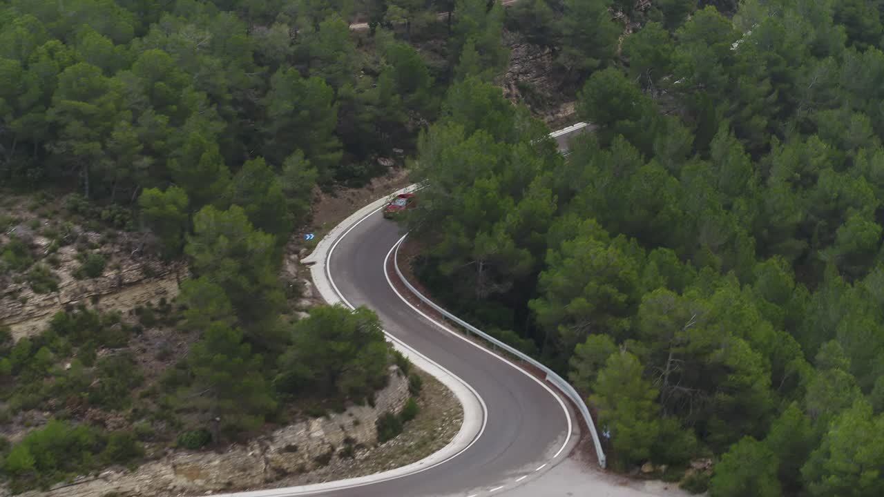 Vista aerea che segue tre auto costose di alta gamma che guidano velocemente lungo le strade tortuose e boschive di Barcellona