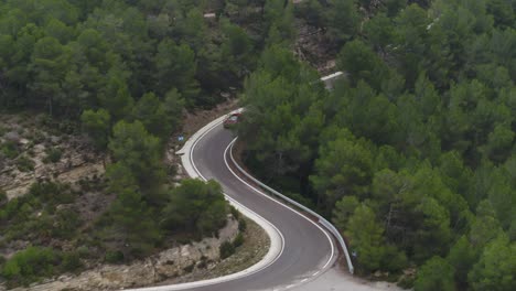 aerial view following three high end expensive cars driving fast along barcelona woodland winding roads