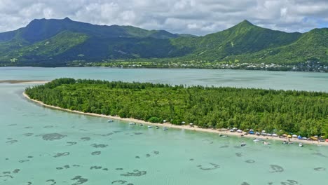 aerial drone above coral reef of mauritius islands blue lagoon, boats, sea life and green mountains with a cloudy blue sky, crystalline water