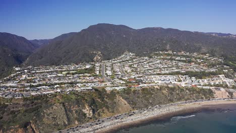 toma aérea súper ancha desde el océano pacífico volando hacia los acantilados de malibu en california
