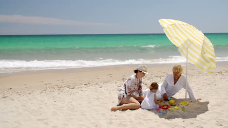 grandma  mom and little girl playing at beach sand