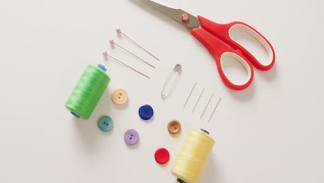 video of scissors, buttons, pins and cotton reels arranged on white background