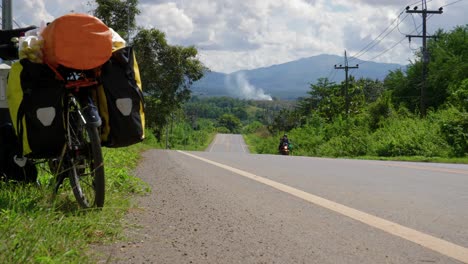 backpacker bicycle parked on the shoulder of a rural road in southeast asia