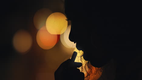 silhouette of woman applying lipstick makeup in city at night preparing for evening party with bokeh lights in background