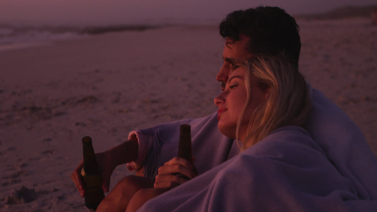 кавказская пара наслаждается временем на пляже во время захода солнца