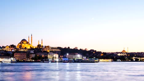 zoom out timelapse view of istanbul cityscape with suleymaniye mosque with tourist ships floating at bosphorus at night
