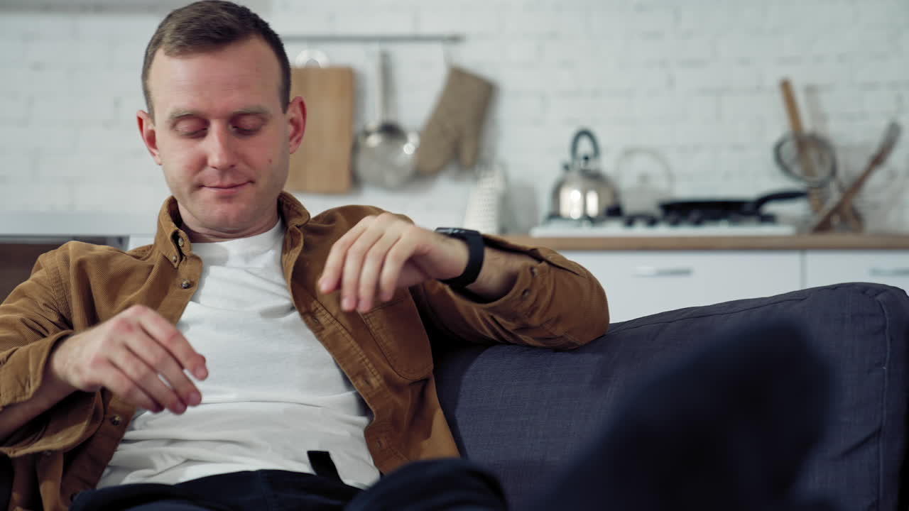 Young freelancer rests on sofa. Tired man puts his laptop off while sitting on the couch at home. Difficult remote job during coronavirus.