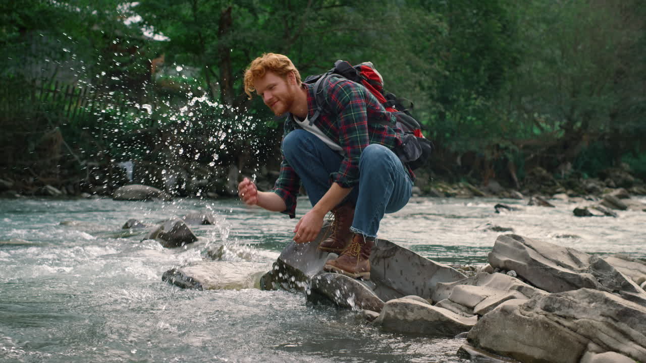 мужчина-путешественник делает перерыв у реки во время похода