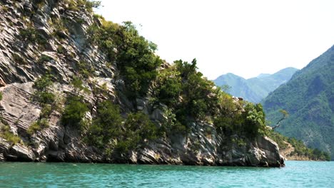 Albania,-Lago-Koman,-Vista-Desde-Un-Ferry-De-La-Orilla-Del-Lago-Y-Los-Picos-De-Las-Montañas-Malditas.