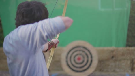 toma en cámara lenta de un hombre disparando una flecha con un arco de madera medieval en un objetivo de práctica