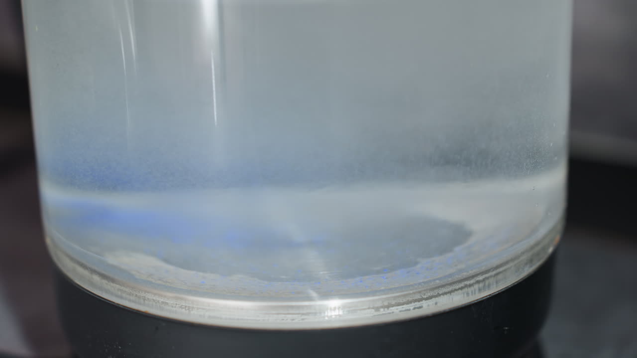 CloseUp Glass Cylinder With Blue Band And Subtle Gradient Layer, Liquid Mixing And Turbidity Shifting Across Clear Sample, Lab Bench Test Scene Showing Monitoring And Quality Inspection For Process