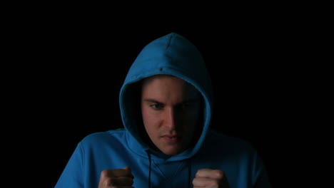 sporty young man boxing on black background