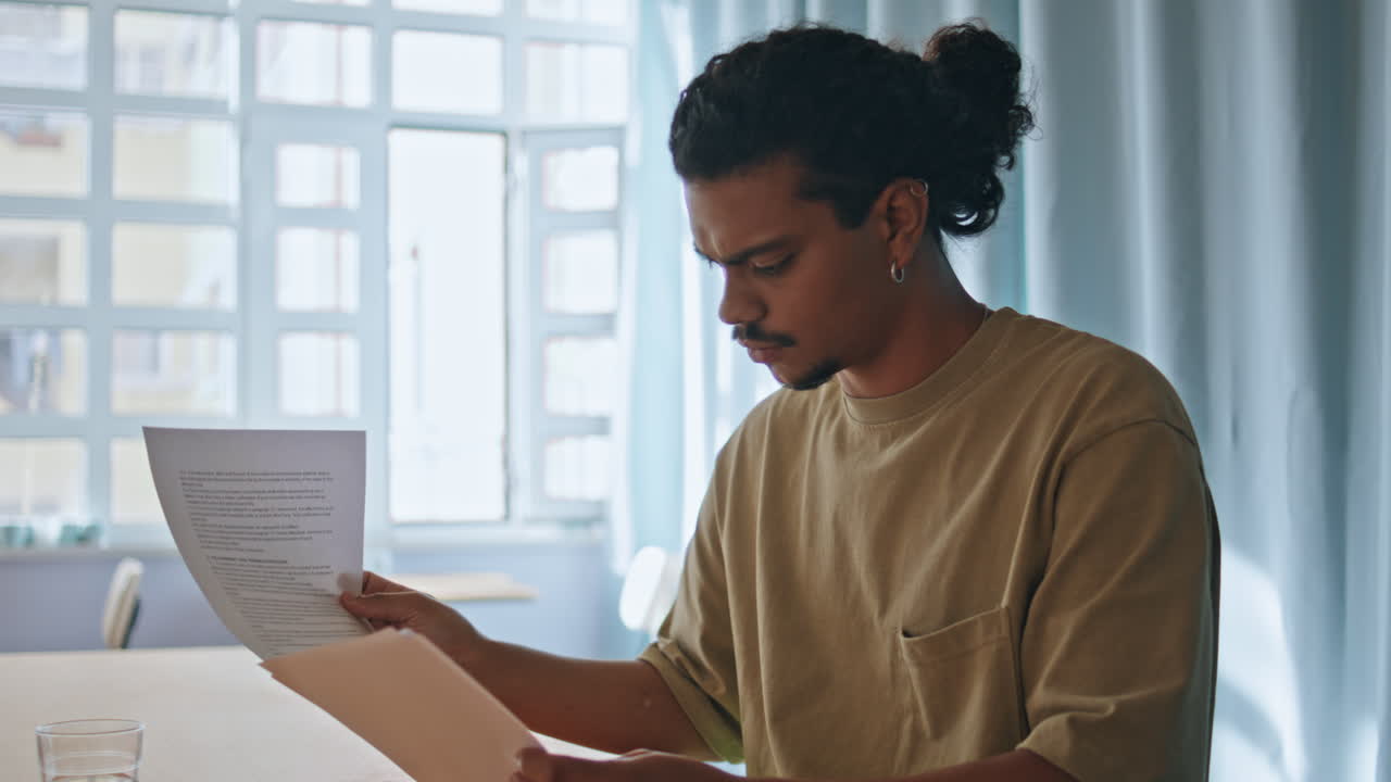 Focused student reading papers information sitting table closeup. Man freelancer