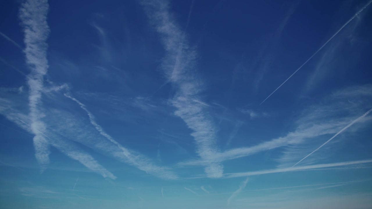 Time lapse di molteplici scie di condensa di aerei che attraversano un cielo azzurro limpido e si disperdono lentamente. Viaggi e trasporti.
