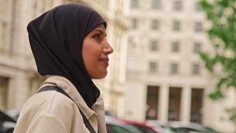 close up portrait of smiling muslim businesswoman wearing hijab and modern business suit standing outside city office buildings 1