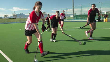 female hockey players competing intensely on outdoor field, focused on game