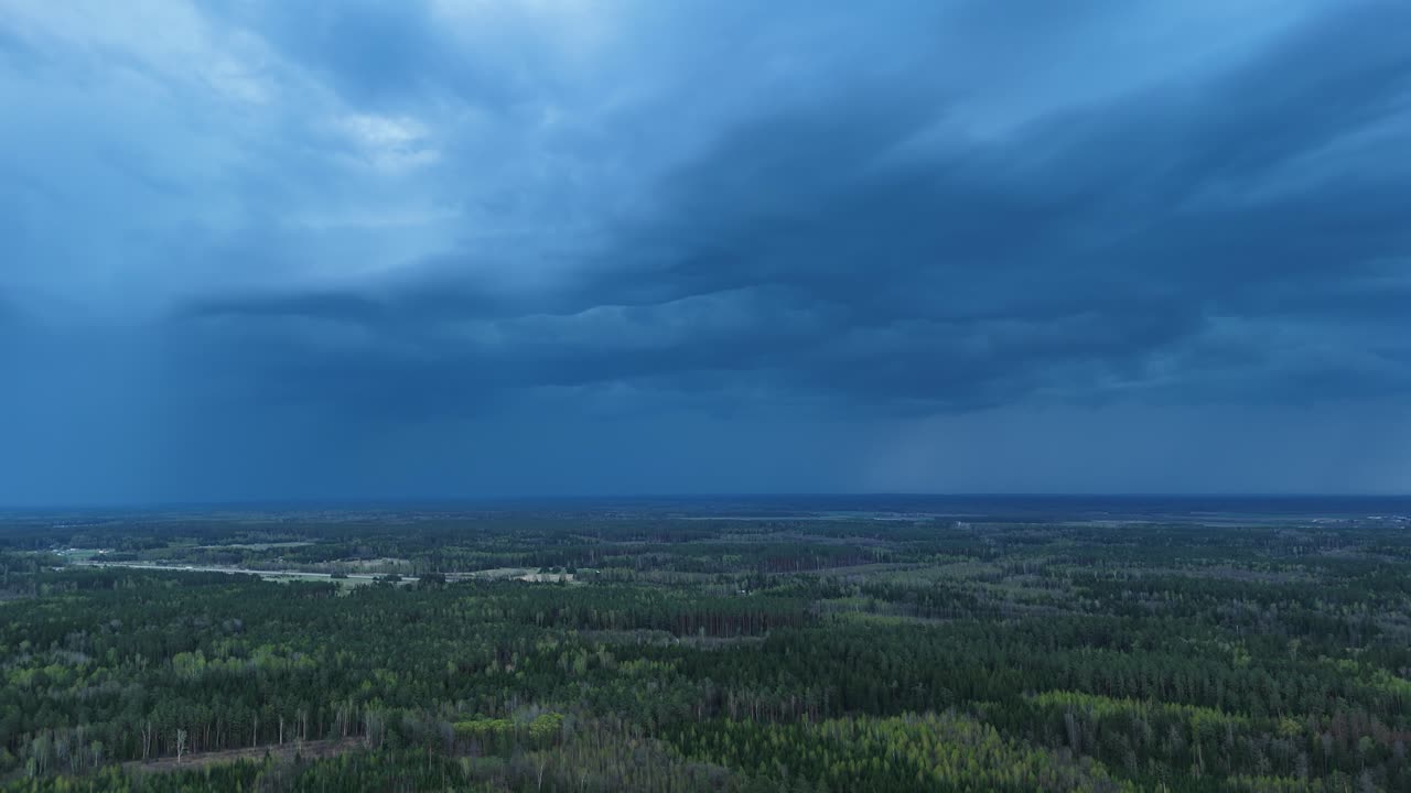 Dark blue thunderstorm clouds flow above countryside landscape