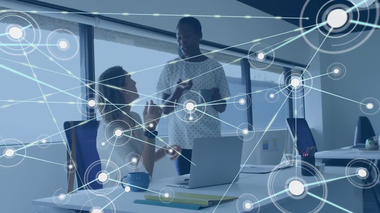 Seated woman gesturing to laptop and starting data nodes linking around colleague in tech project