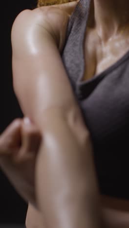 vertical video close up studio shot showing chest and abdomen of mature woman wearing gym fitness clothing doing stretching exercises