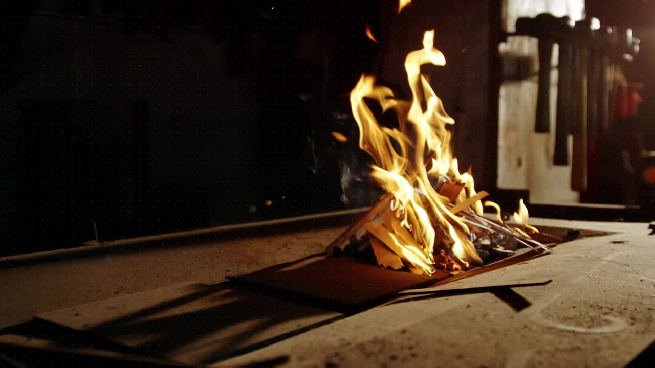 Burning wood-cardboard scraps sparking red cyan shapes pulsing fading as flames flickering on metal