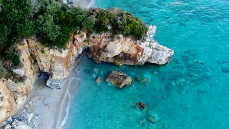 Sandy-beach-with-rock-cave-and-turquoise-sea-filmed-in-the-evening-light