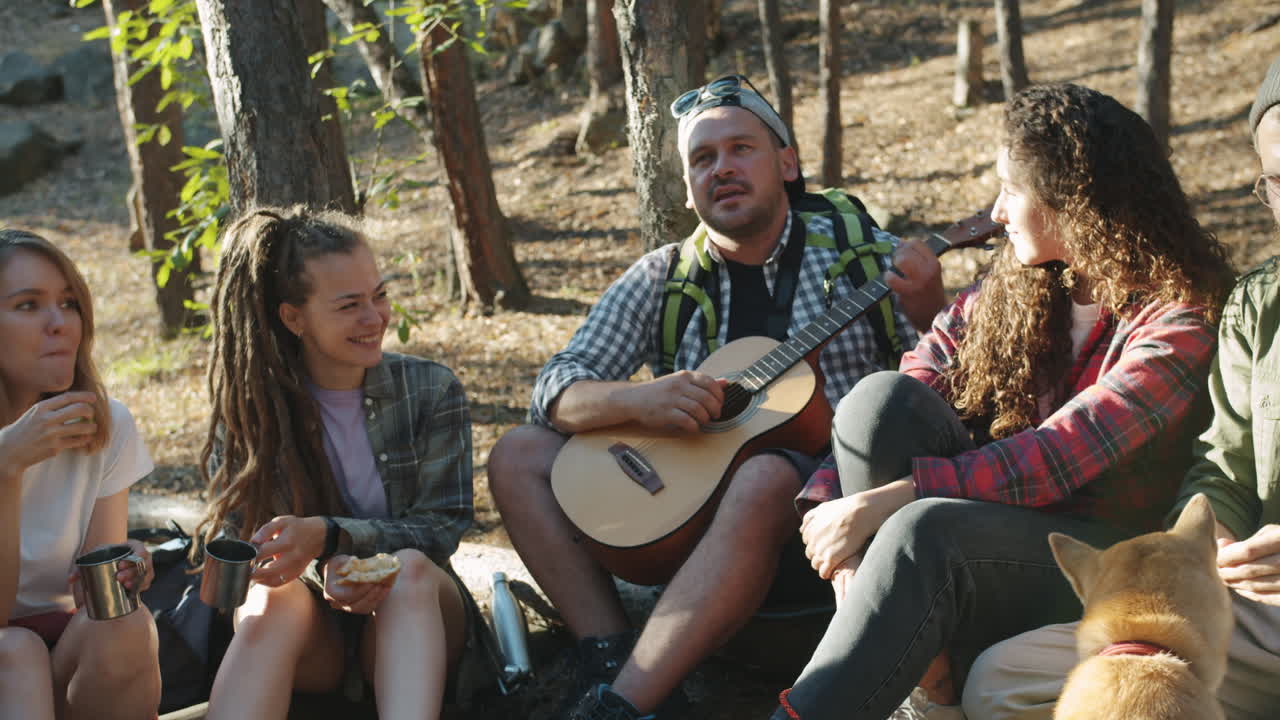 Venner nyter en piknik og musikk i skogen