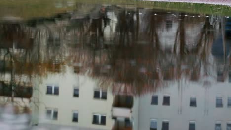 Herbstliche-Pfützenreflexion-Eines-Grauen-Vorortgebäudes-In-Berlin,-Deutschland