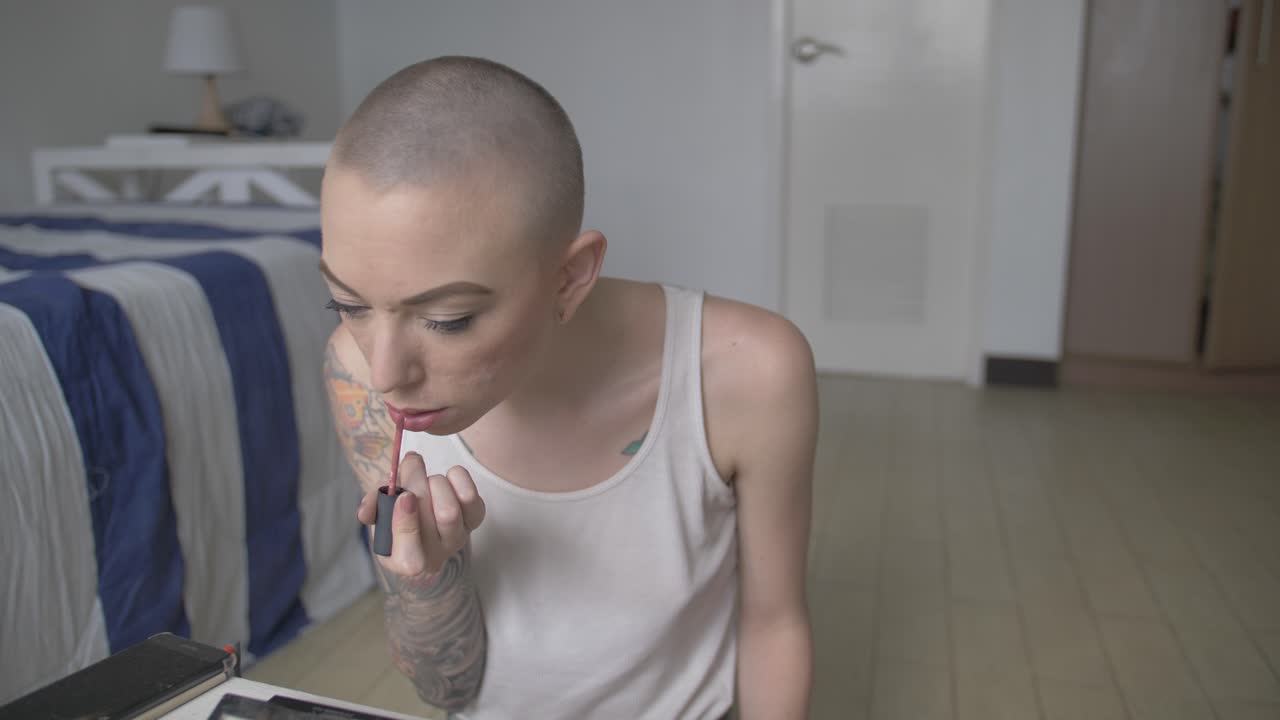 женщина в белом топе сидит на полу и наносит макияж