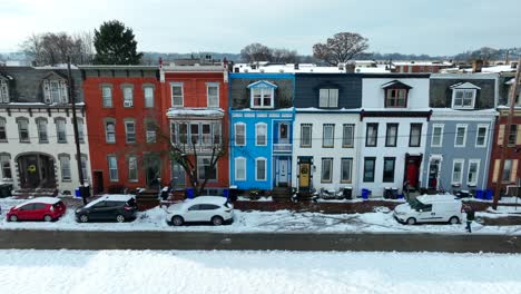 snow covered colorful row houses and parked cars on a clear winter day