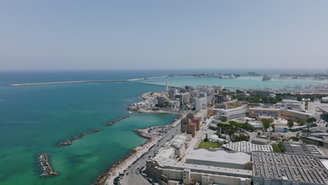 Wide-aerial-showing-the-Adriatic-Sea,-midday-traffic-and-the-lighthouse-outside-of-Bari,-Italy