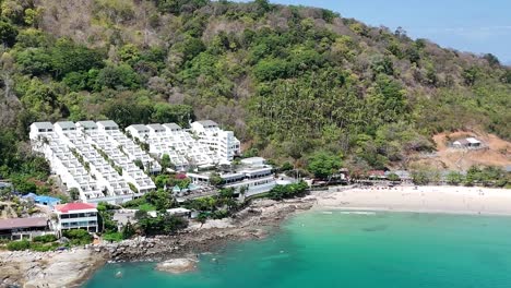 las imágenes de drones capturan la serena costa de phuket, tailandia, mostrando vegetación exuberante, aguas turquesas y barcos anclados bajo cielos despejados.