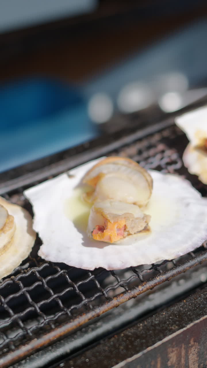 Grilled scallops and ell served on shells at the Tsukiji Fish Market in Japan. Vertical