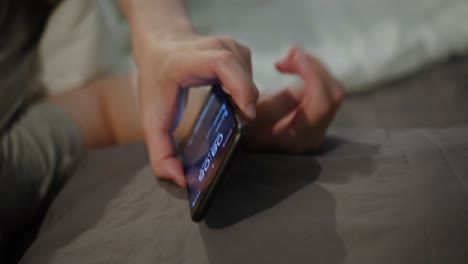 person lying in bed checking phone