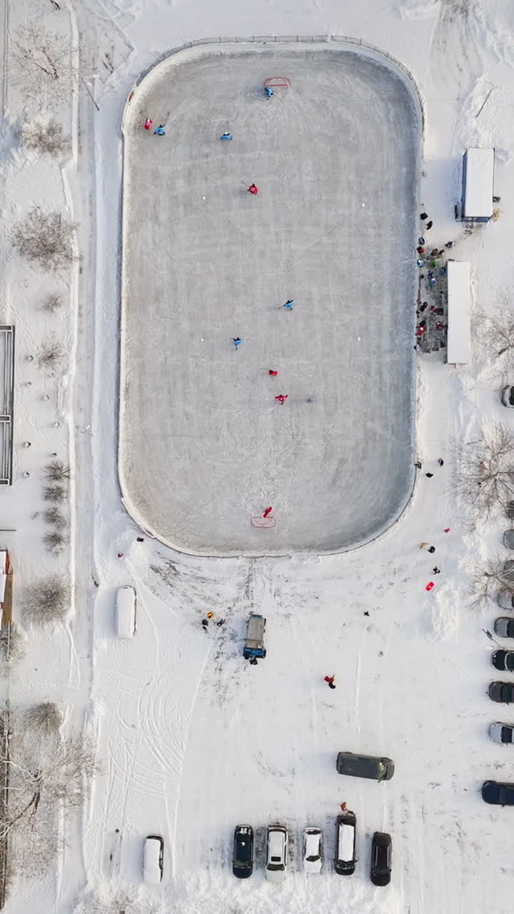 Top down aerial portrait over a ice hockey game at a outdoor rink, winter day