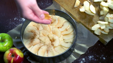 esparciendo polvo de canela en la tarta de manzana. haciendo tarta de manzana dulce