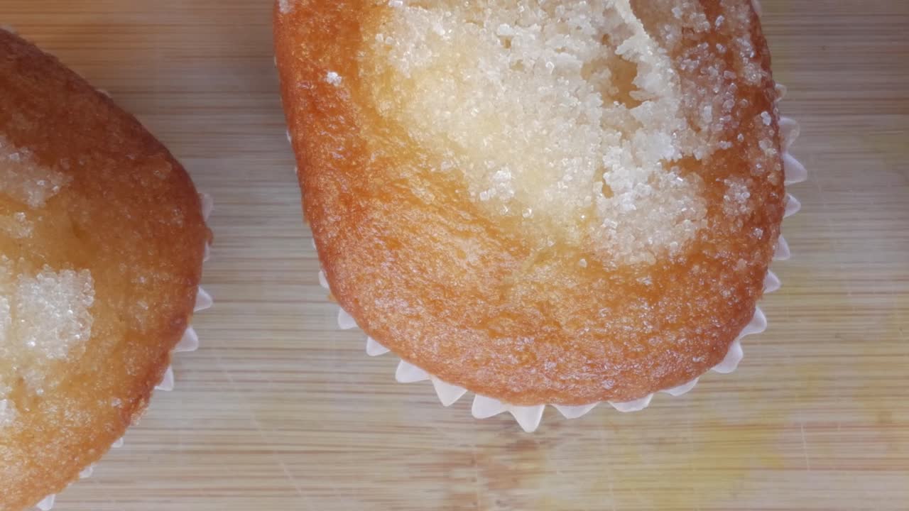 Close-up of sugar-topped muffins on wooden surface, warm and inviting