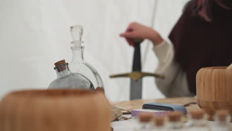 Female-warrior-sits-at-table-with-ingredients-for-potion