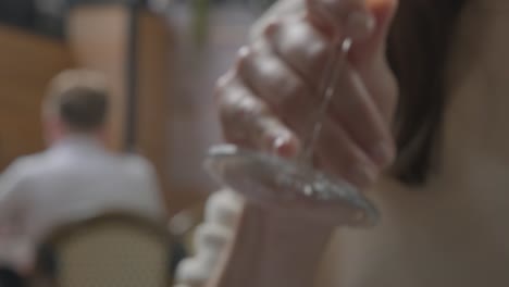mano de mujer alcanzando y bebiendo su burbujeante vino rosado