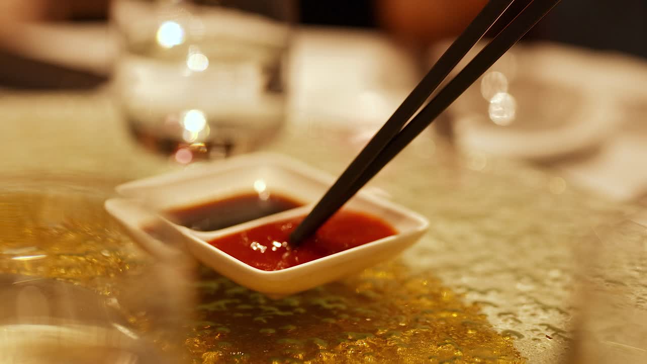 Chopsticks stirring sauce in a dimly lit Gold Coast restaurant, creating a warm and inviting atmosphere
