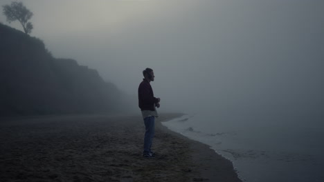 stylish guy listening music in headphones on beach. man dancing in music rhythm