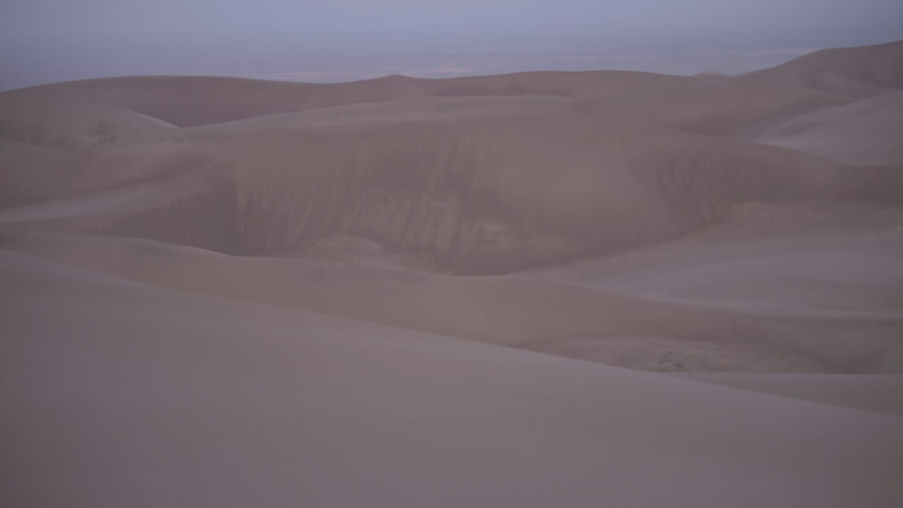 panorámica hasta la luna crepuscular que se cierne sobre el campo de dunas de arena