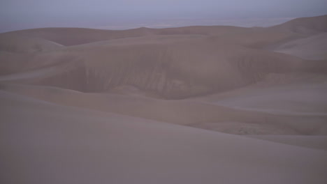 Panorámica-Hasta-La-Luna-Crepuscular-Que-Se-Cierne-Sobre-El-Campo-De-Dunas-De-Arena