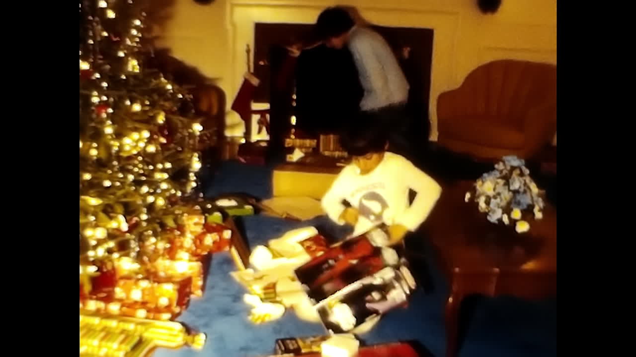 Two Boys Sitting Next to Christmas Tree. CIRCA USA - 1970s: A 1970s video archive from the USA featuring a couple of boys sitting next to a decorated Christmas tree.