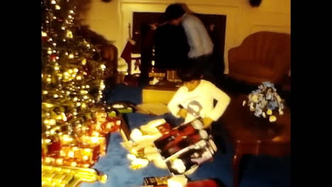 two boys sitting next to christmas tree. circa usa - 1970s: a 1970s video archive from the usa featuring a couple of boys sitting next to a decorated christmas tree.