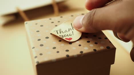 person placing a thank you note on a gift box